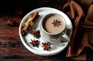 Koyu ahşap arka planda, baharatlı seramik bardakta Masala çayı.