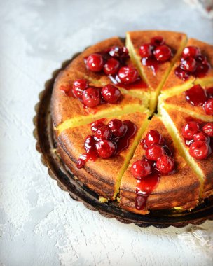 Gri arka planda kiraz soslu süzme peynir güveci.