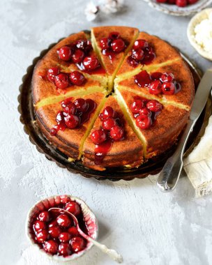 Gri arka planda kiraz soslu süzme peynir güveci.