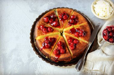 Gri arka planda kiraz soslu süzme peynir güveci.