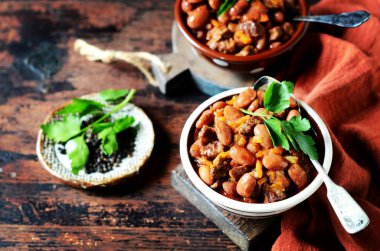 Siyah ahşap arka planda fasulyeli, domatesli ve sebzeli biftek yahnisi.