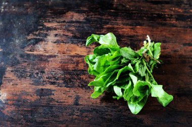 Koyu ahşap arka planda bir demet taze ıspanak.