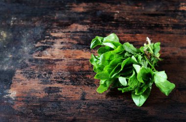 Koyu ahşap arka planda bir demet taze ıspanak.