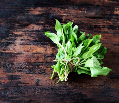 Koyu ahşap arka planda bir demet taze ıspanak.