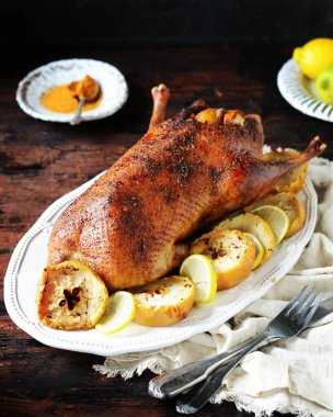 Koyu ahşap bir masada elmalı ve limonlu geleneksel fırında ördek.