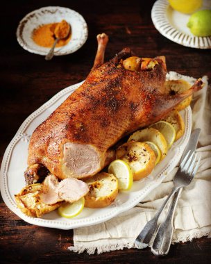 Koyu ahşap bir masada elmalı ve limonlu geleneksel fırında ördek.
