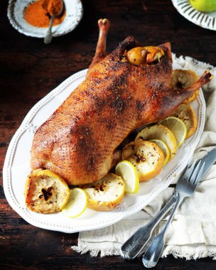 Koyu ahşap bir masada elmalı ve limonlu geleneksel fırında ördek.