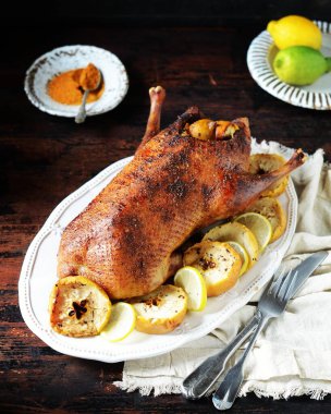 Koyu ahşap bir masada elmalı ve limonlu geleneksel fırında ördek.
