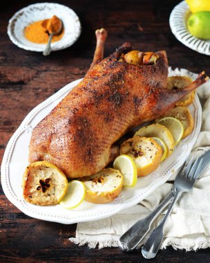 Koyu ahşap bir masada elmalı ve limonlu geleneksel fırında ördek.