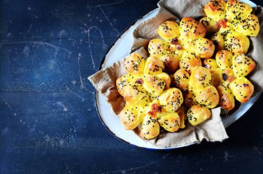 Kuru üzümlü ev yapımı çörekler ve koyu mavi ahşap arka planda susam tohumları.