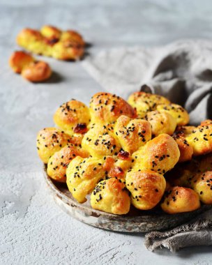 Üzümlü ev yapımı çörekler ve gri ahşap arka planda susam tohumları.