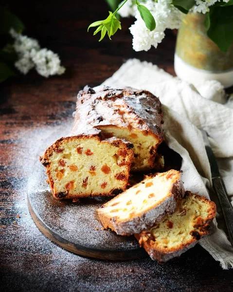 Kuru Üzümlü Kremalı Pasta Koyu Arkaplanlı Leylak Çiçekli Bir Kesim — Stok fotoğraf