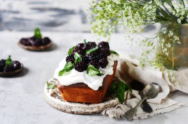 Kremalı ve böğürtlenli kek gri arka planda, durgun hayat