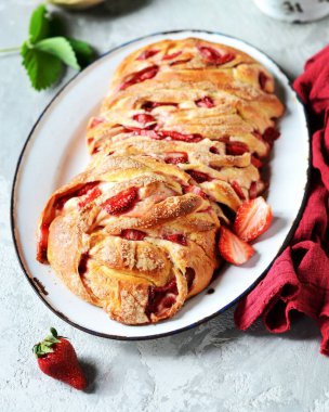 Gri arka planda bir tabakta çilekli ve şekerli maya babka.