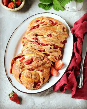 Gri arka planda bir tabakta çilekli ve şekerli maya babka.