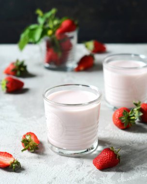 Gri arka planda cam bardaklarda çilekli smoothie.
