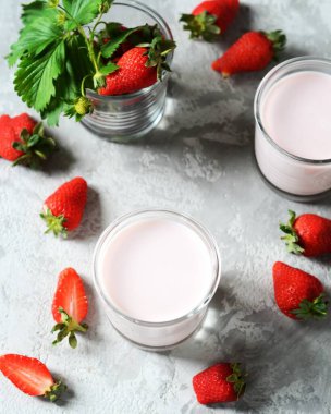 Gri arka planda cam bardaklarda çilekli smoothie.