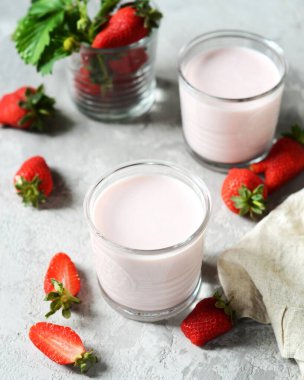 Gri arka planda cam bardaklarda çilekli smoothie.