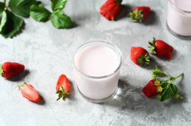 Gri arka planda cam bardaklarda çilekli smoothie.