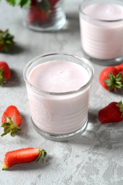 Gri arka planda cam bardaklarda çilekli smoothie.