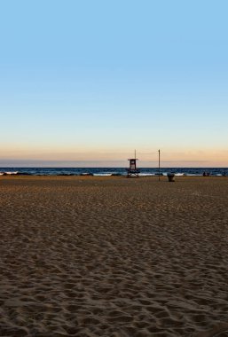 Pasifik Okyanusu 'nun üzerinde gün batımında kızıl bir gökyüzü ve Kaliforniya' da Newport sahilinde yalnız bir palmiye ağacı. Cankurtaranların işi bitti.