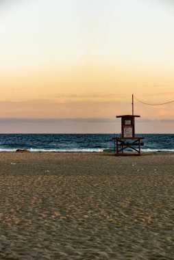 Pasifik Okyanusu 'nun üzerinde gün batımında kızıl bir gökyüzü ve Kaliforniya' da Newport sahilinde yalnız bir palmiye ağacı. Cankurtaranların işi bitti.