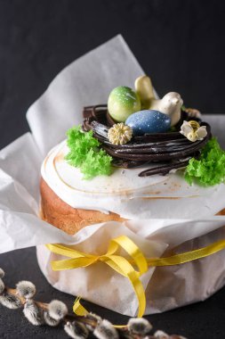 Paskalya, arka planda Paskalya pastası, yumurtalarla süslenmiş çikolata yuvası ve bir çikolata kuşu, güzel manzara, yumuşak odak
