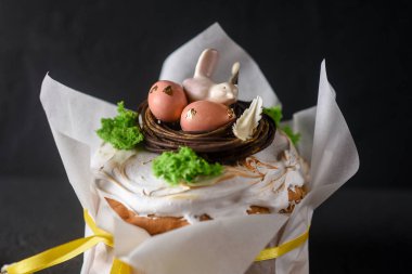 Paskalya, arka planda Paskalya pastası, yumurtalarla süslenmiş çikolata yuvası ve bir çikolata kuşu, güzel manzara, yumuşak odak