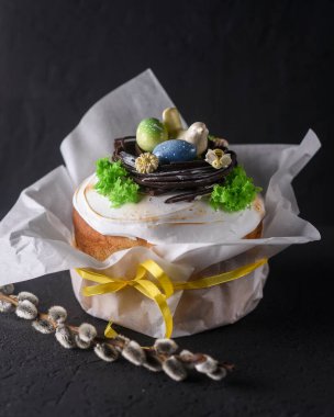 Paskalya, arka planda Paskalya pastası, yumurtalarla süslenmiş çikolata yuvası ve bir çikolata kuşu, güzel manzara, yumuşak odak