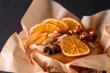 Karanlık bir arka planda paskalya pastası, güzel bir manzara, karamelize edilmiş, kurutulmuş meyve, fındık, yumuşak odak, kabartma kağıdına sarılmış