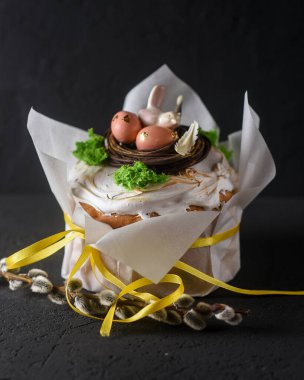 Paskalya, arka planda Paskalya pastası, yumurtalarla süslenmiş çikolata yuvası ve bir çikolata kuşu, güzel manzara, yumuşak odak