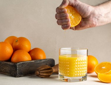 Portakalın yarısından taze portakal suyu sıkmak kristal bardakta ve ahşap kutuda fırfırlı portakallar..