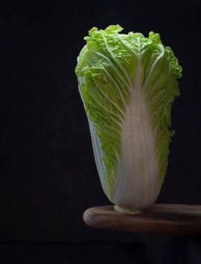 Taze, olgun Çin lahanası ahşap masa üzerinde siyah arka plan. Karanlık ruh hali sebzeleri konsepti..