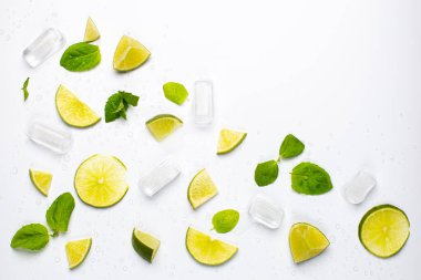 Taze limon dilimleri, nane yaprakları, buz küpleri ve su damlalarıyla beyaz ferahlatıcı gıda arka planı..