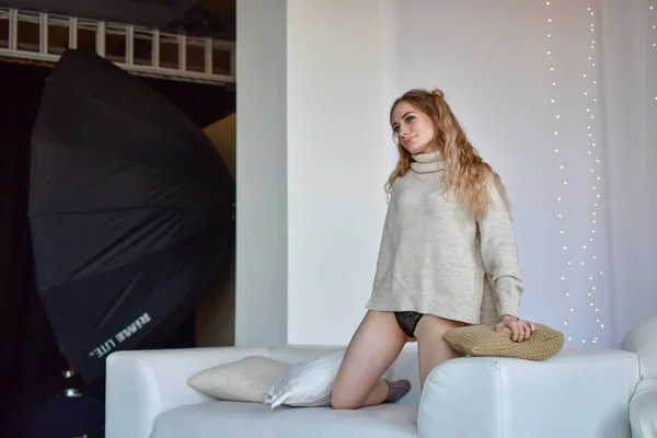 Sexy dívka ležící na pohovce a hraje se s polštářem ve svetru — Stock fotografie