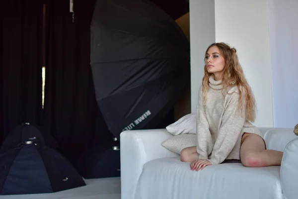 Сексуальная девушка лежит на диване в свитерах и носках и в черном и — стоковое фото