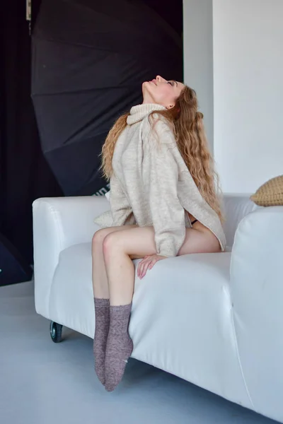 Sexy chica se sienta en poses eróticas con las piernas separadas en el sofá en —  Fotos de Stock