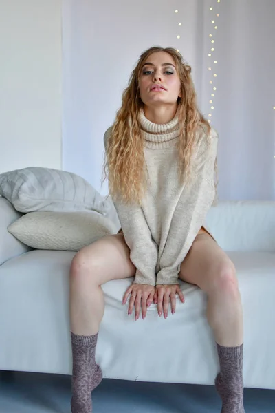 性感的女孩坐在性感的姿势里，双腿分开在沙发上 — 图库照片