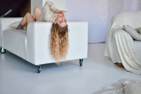 Seksi kız yalan söylüyor Uzun saçlı kanepede uyur kazaklarla — Stok fotoğraf