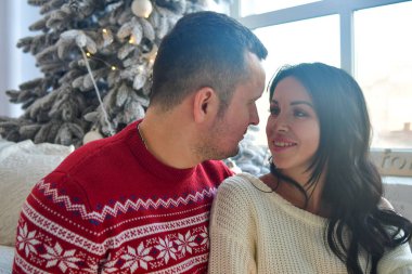 Çift Noel ağacını çelenklerle süslüyor. Seksi esmer ve Noel ağacının önündeki adam.