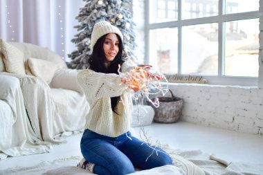 Kız Noel ağacını çelenklerle süslüyor.