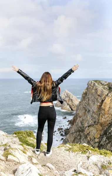 Mujer joven mirando al horizonte con los brazos levantados — Foto de Stock