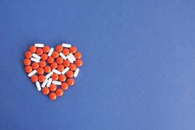Kırmızı tabletler ve bir şeyl, bir kalp mavi zemin üzerine beyaz hap