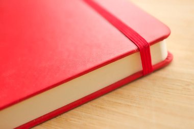 Ahşap masaya yakın plan kırmızı çizim defteri. Resim, çizim ve yazma için şık bir defter.