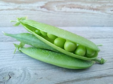 Eski ahşap bir yüzey üzerinde yeşil bezelye kabukları. Yaklaş.