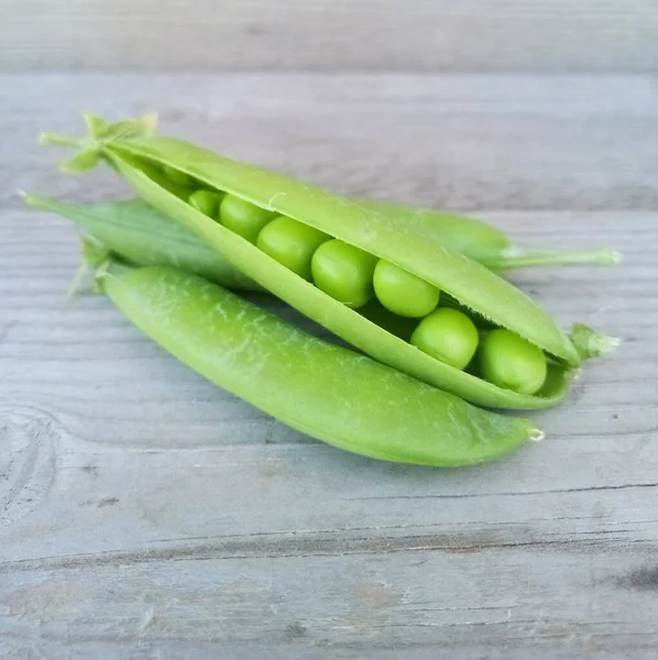 Pods of green peas on a old wooden surface close up — Stock Photo, Image