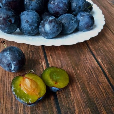 Organik, taze, olgun erik. Beyaz bir tabakta bir damla su..