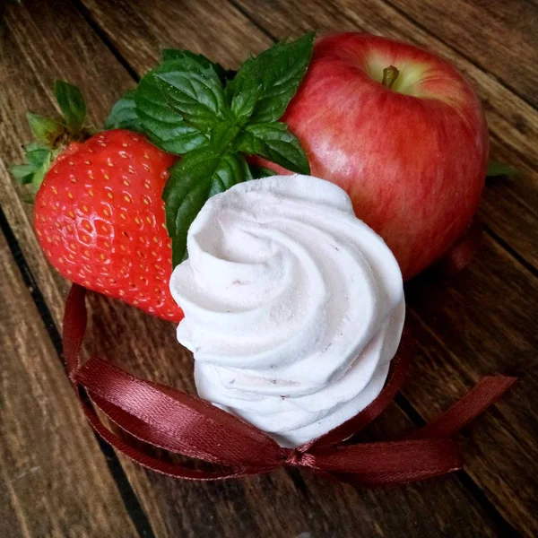 Elma ve çilekli şekerlemeler ahşap masada.