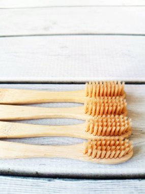 Beyaz ahşap zemin üzerinde dört ahşap diş fırçasından oluşan bir aile seti. 