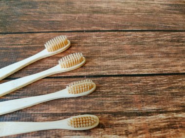 Tahta arka planda dört ahşap diş fırçasından oluşan bir aile seti. 